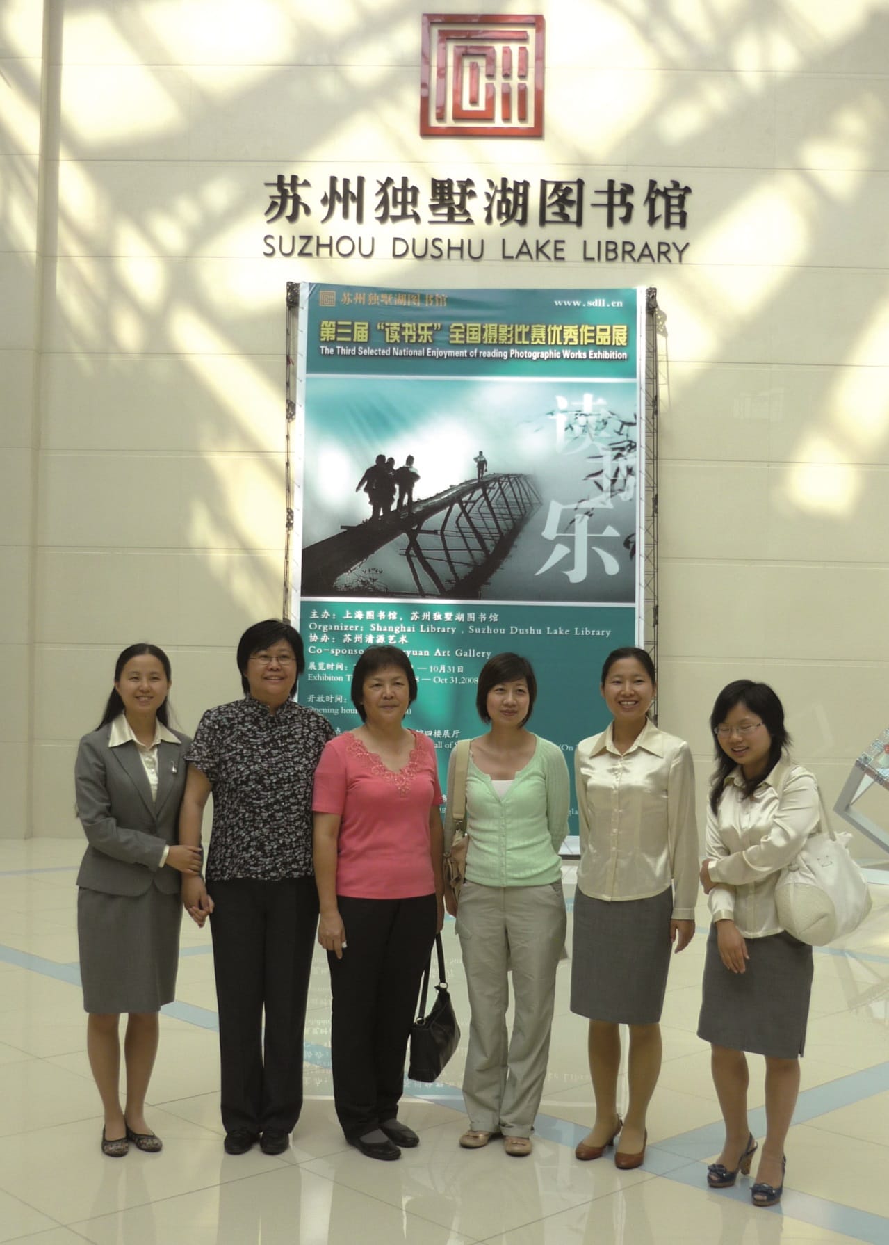 Five people standing in front of a poster at Suzhou Dushu Lake Library.